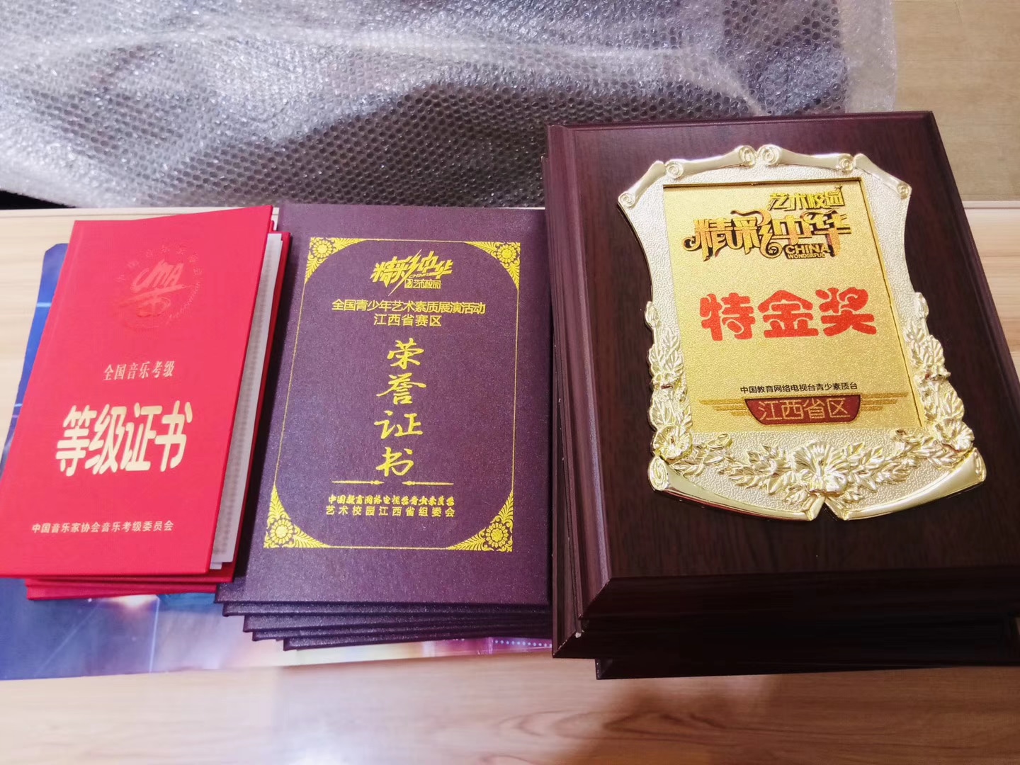 桌面陈列真实音乐考级证书、荣誉证书与比赛奖牌,完整保留奖项文字
